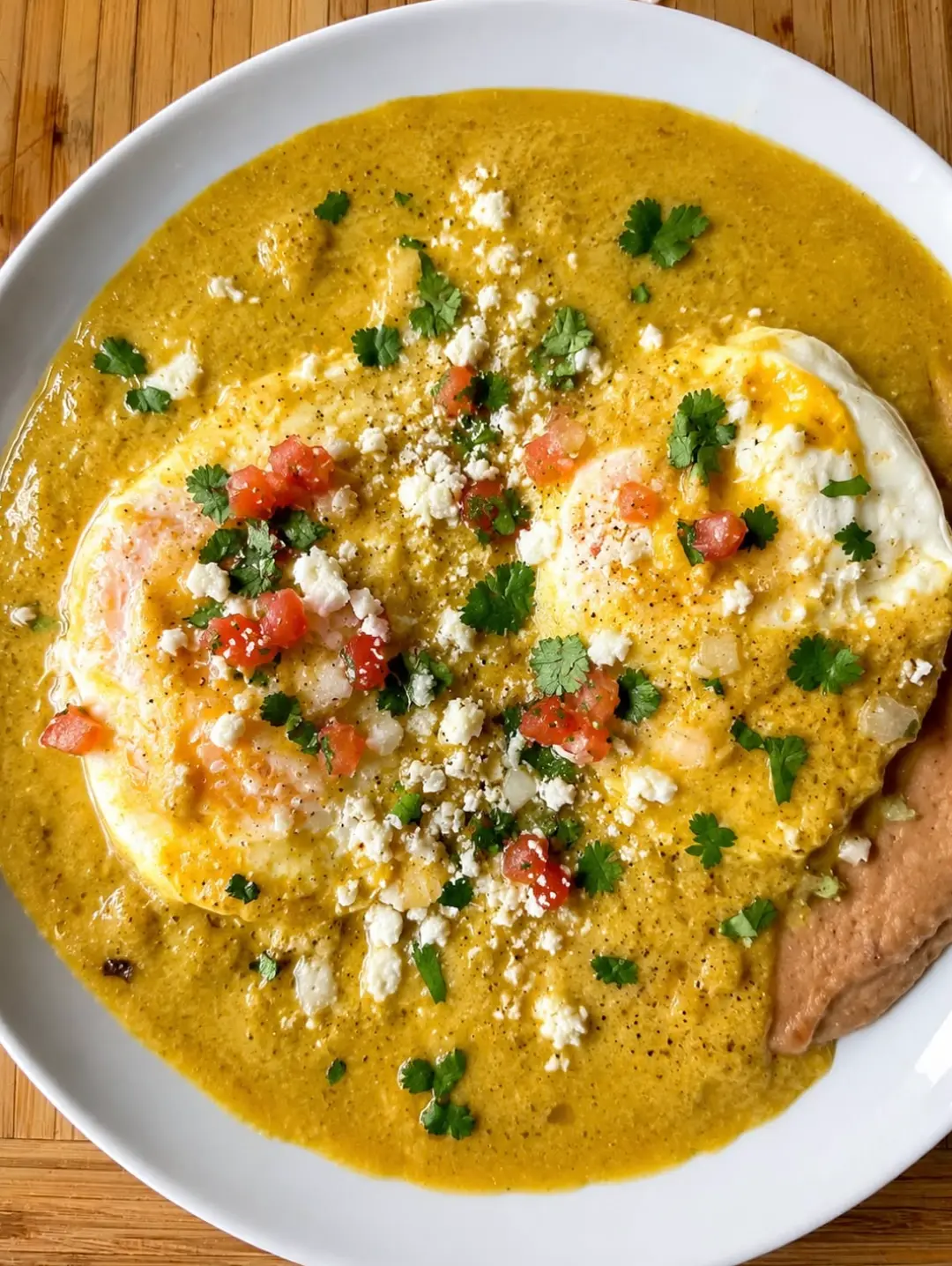 Plate of huevos rancheros smothered in bright Salsas Guti salsa verde with queso fresco
