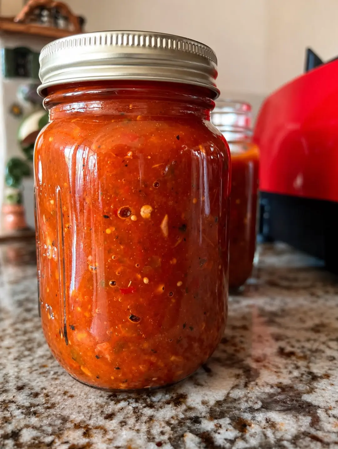 Mason jar of rustic stone-ground Salsas Guti molcajete salsa on a kitchen counter